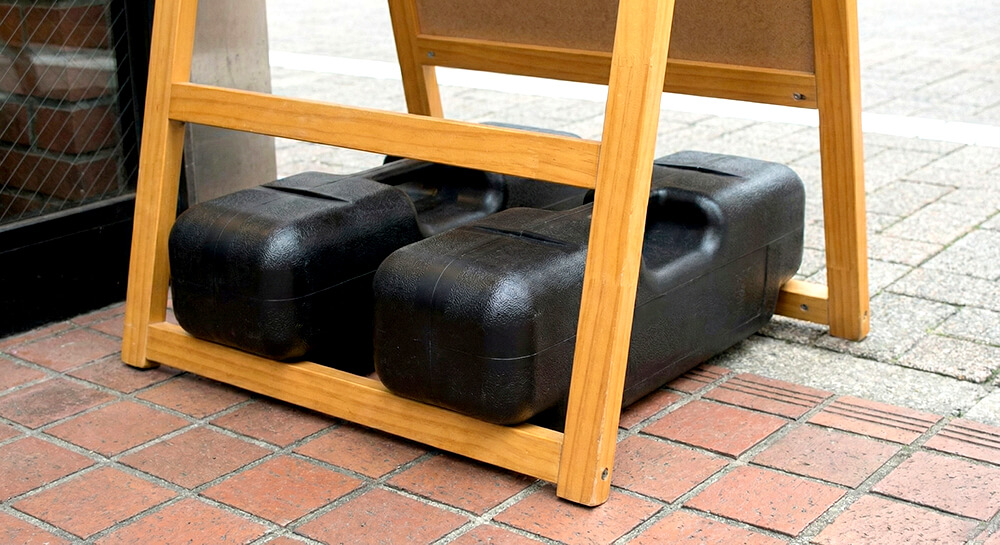 強風で看板が倒れないようにウエイトを設置している様子