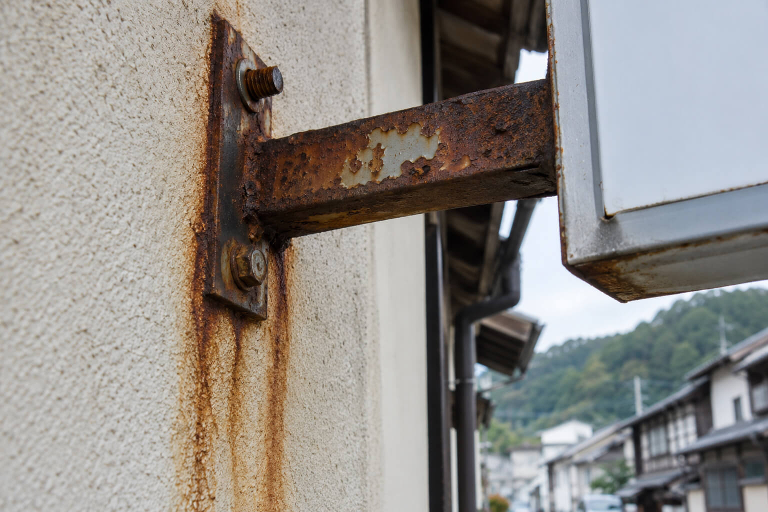 サビて変色し、ボルトが緩んだ袖看板の取付金具のアップ