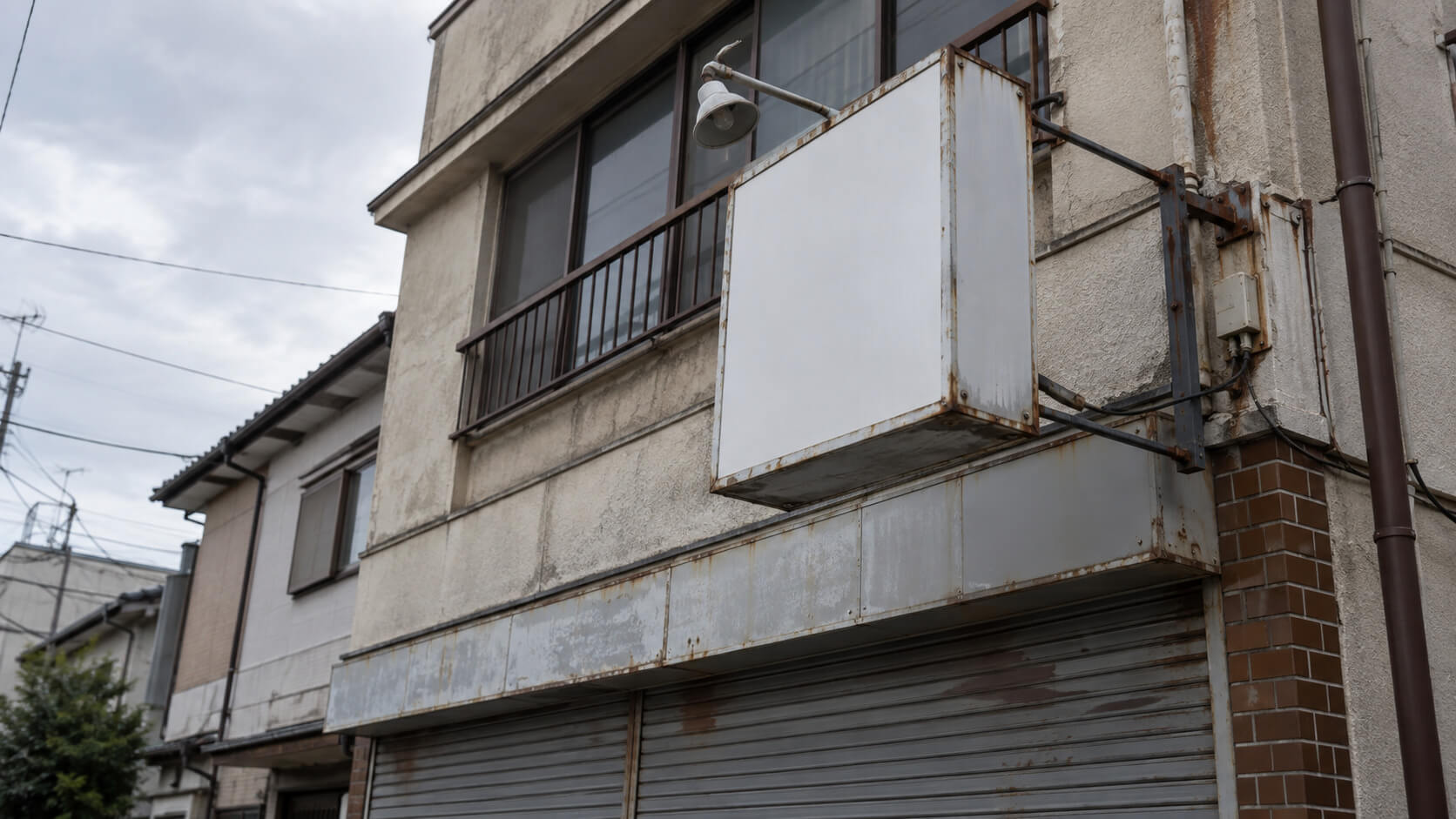 撤去前の現地調査で看板の固定金具と配線を確認する職人