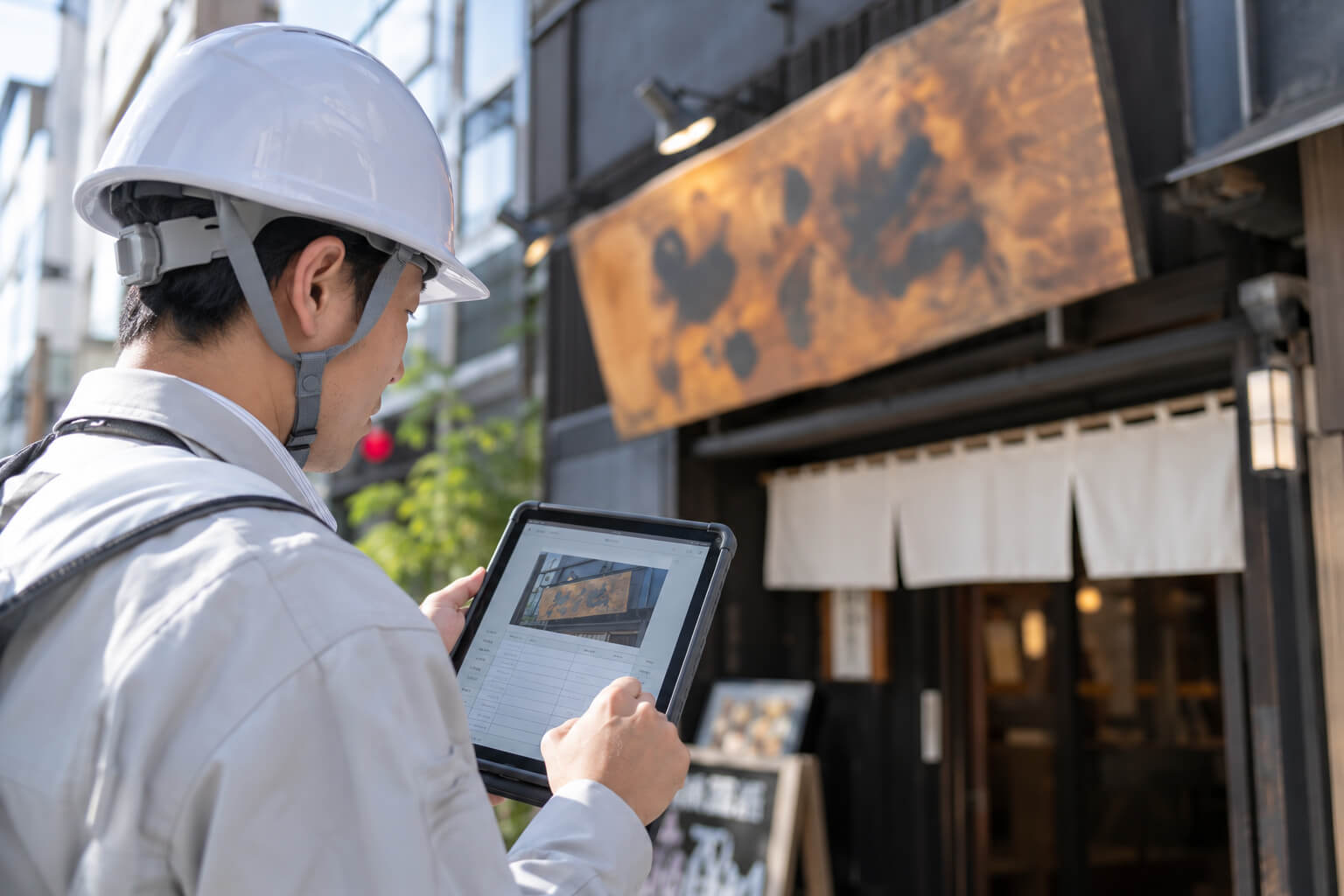 点検員がタブレットに看板の点検項目と写真を記録している様子