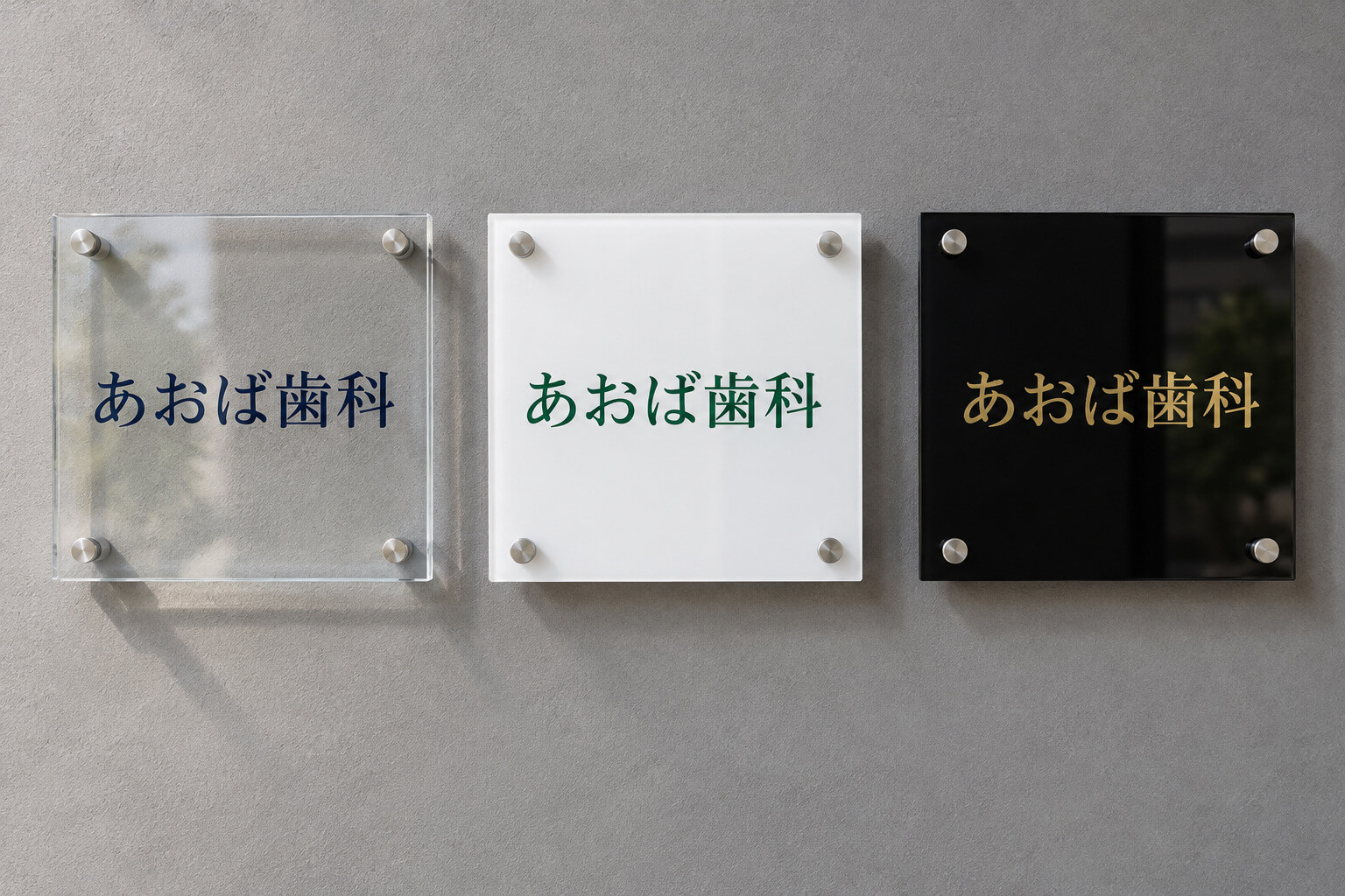 透明・白・黒の3種類のアクリル板で作った看板を、同じ壁に並べて比べた様子