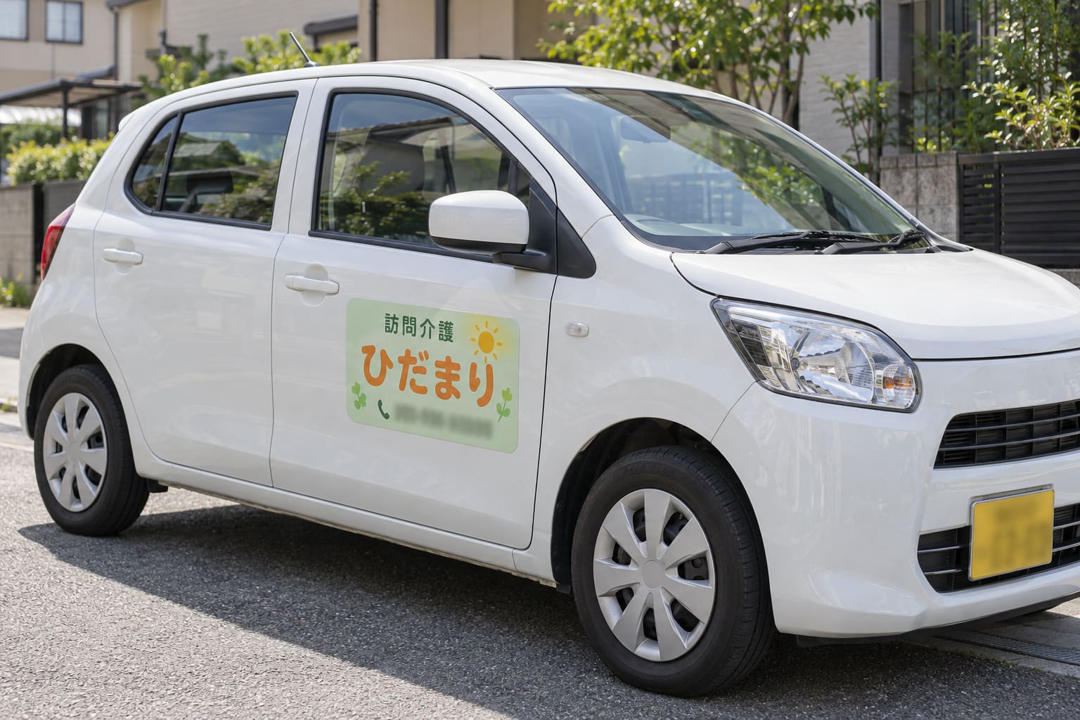 白い軽自動車のドアに、淡い緑の地に丸みのある書体で「訪問介護 ひだまり」と書かれたマグネットが貼られている様子