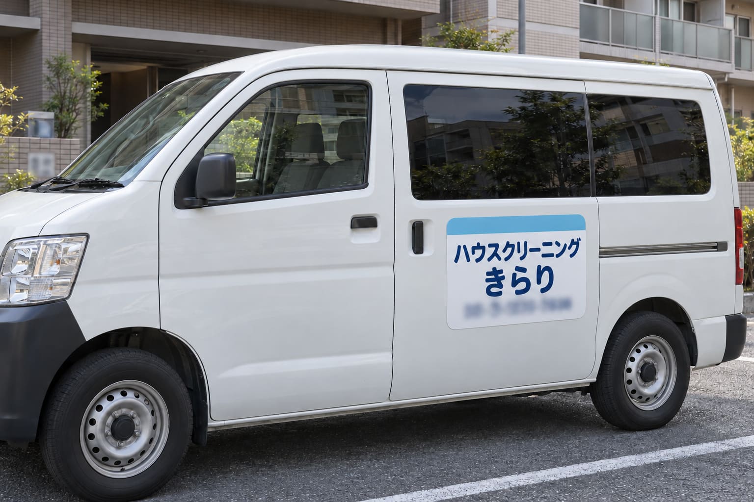 白いワンボックス車のスライドドアに、水色の帯と「ハウスクリーニング きらり」の大きな文字、電話番号が入ったマグネットが貼られている様子
