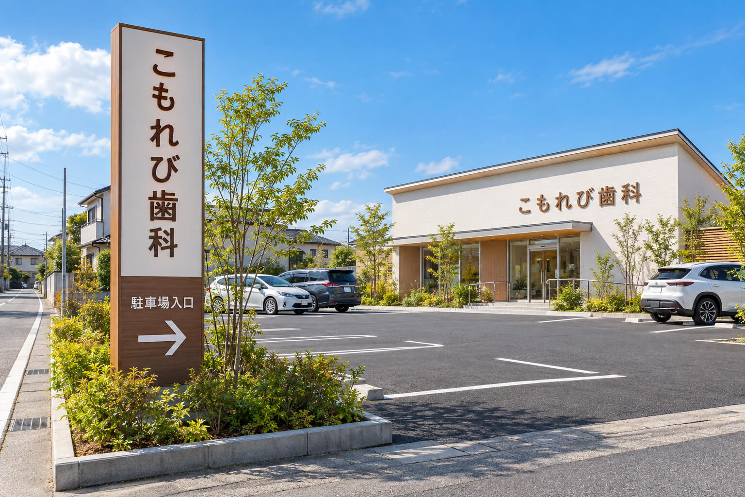 郊外のクリニックの駐車場の入口に立つ自立看板と、建物の壁面に取り付けた院名の切り文字