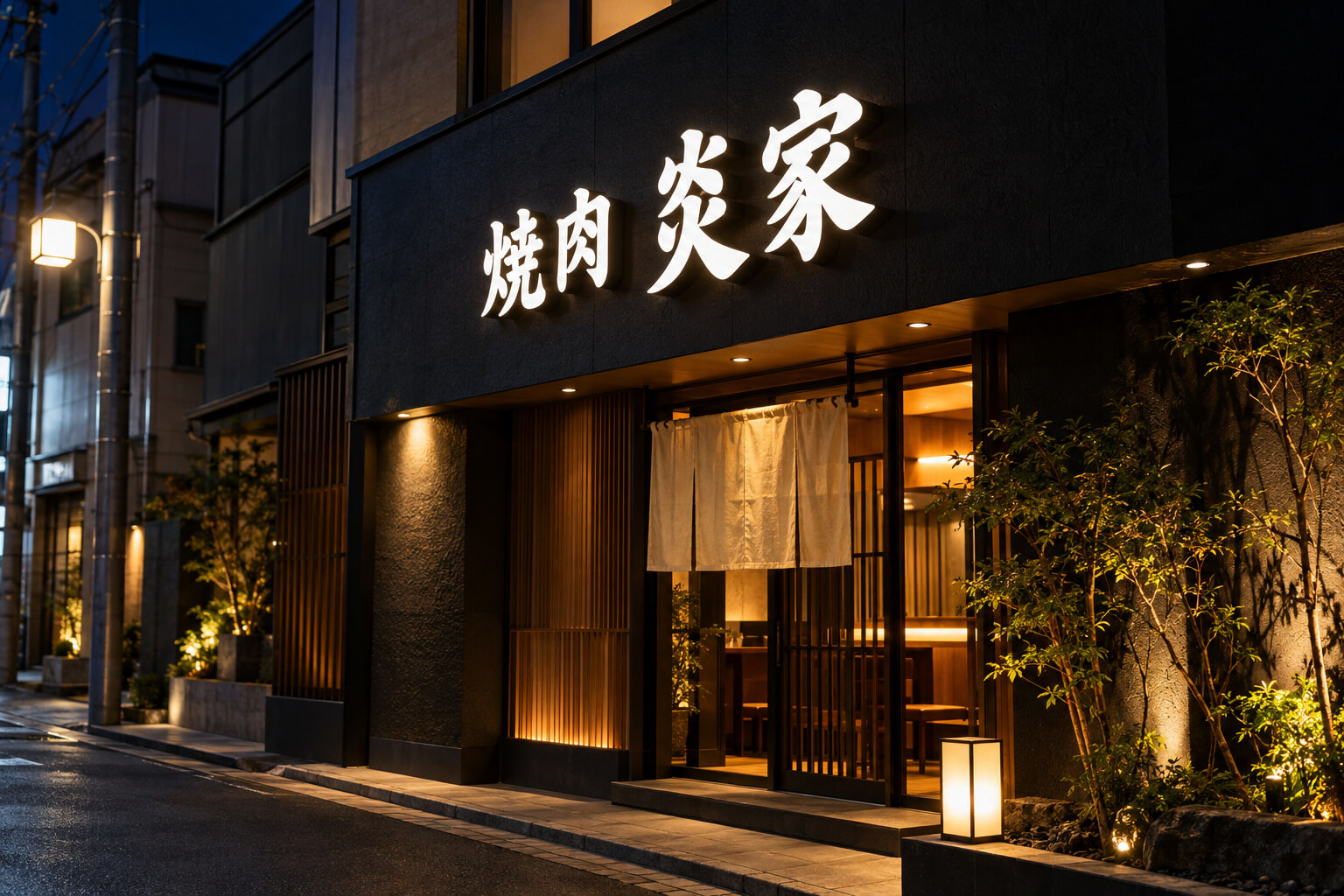 夜の店舗の外壁で、箱型の文字一つひとつが内側から白く光っている箱文字（チャンネル文字）の看板