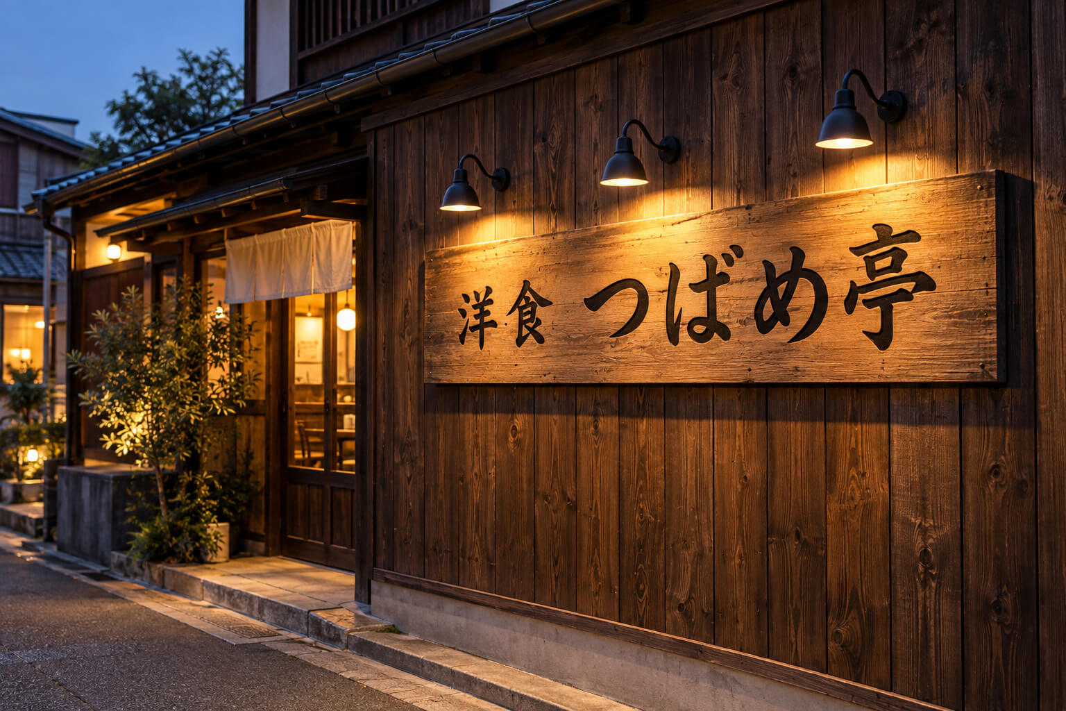レトロな雰囲気の店舗の壁面看板を、黒いアームライト3灯が上から照らしている様子