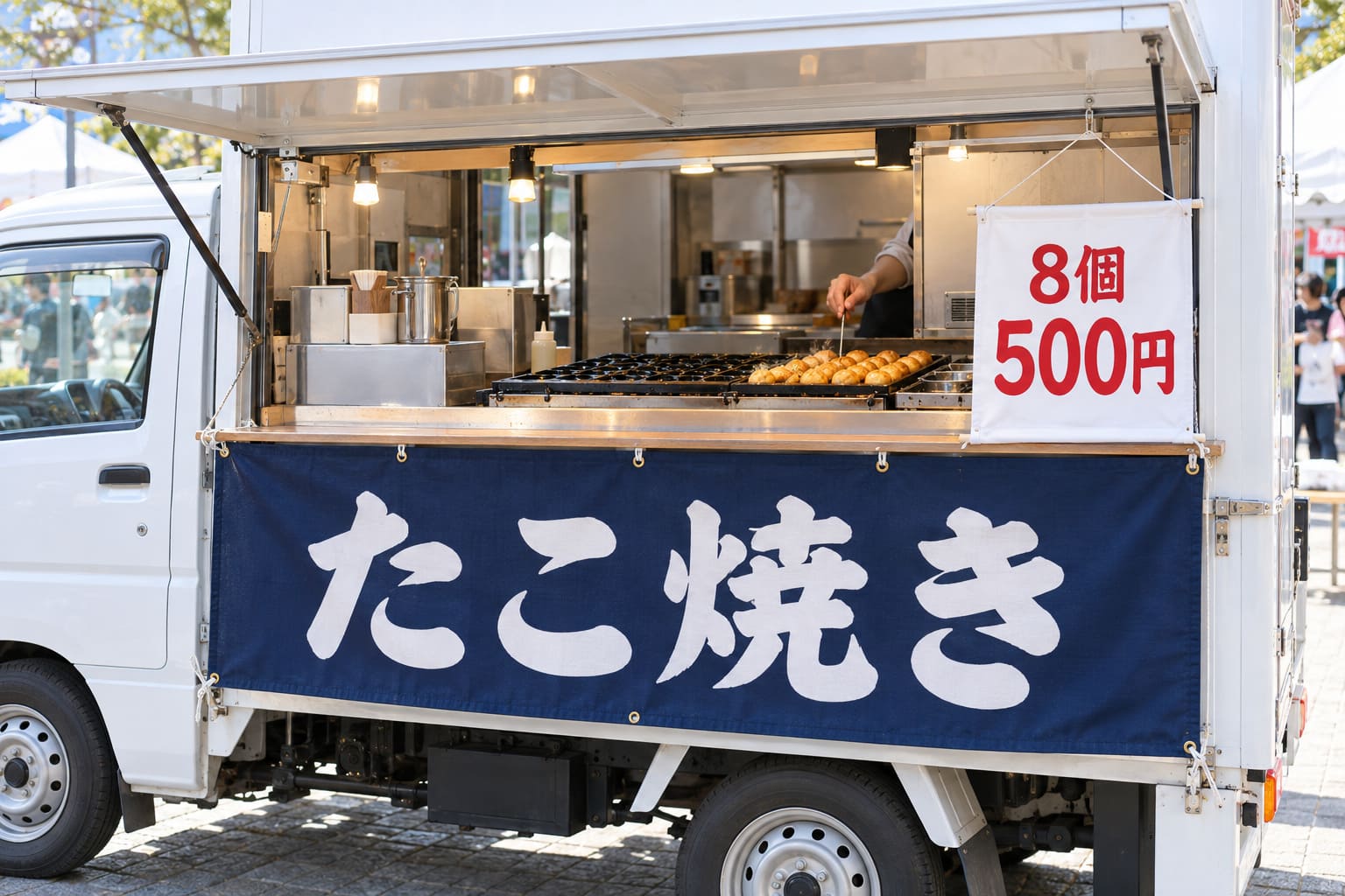 販売窓の下に店名の横長の幕、カウンターの前に値段を書いた小さな幕を付けた、たこ焼きのキッチンカー