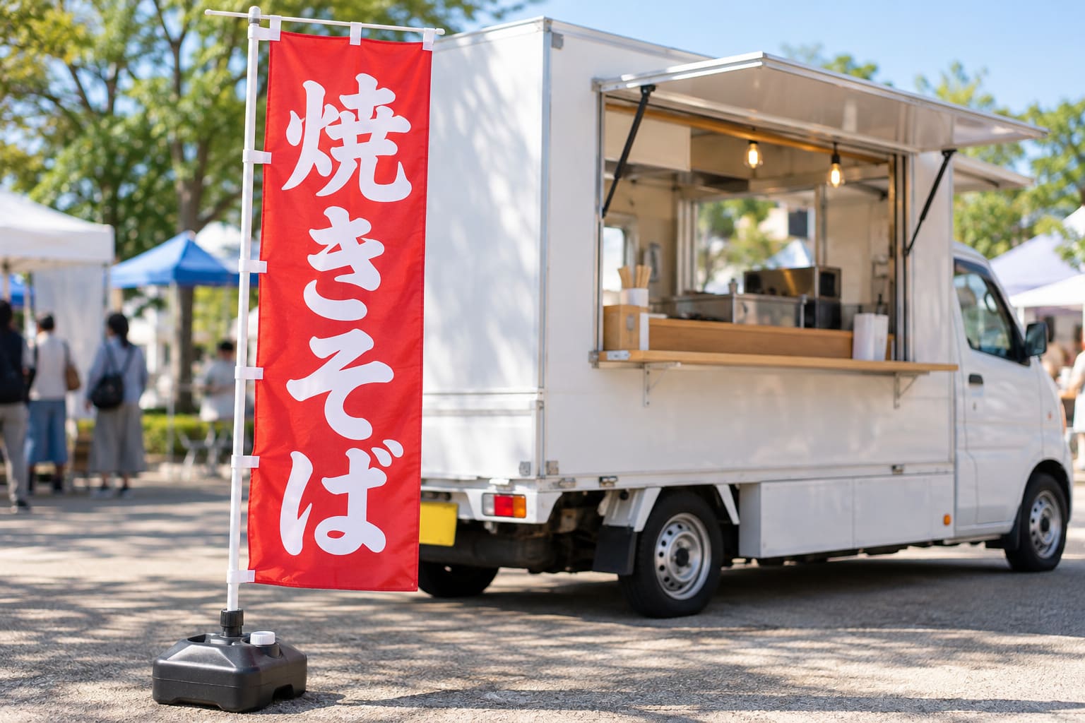 キッチンカーの横の通路側に、水を入れた注水台で立てた縦長ののぼり旗