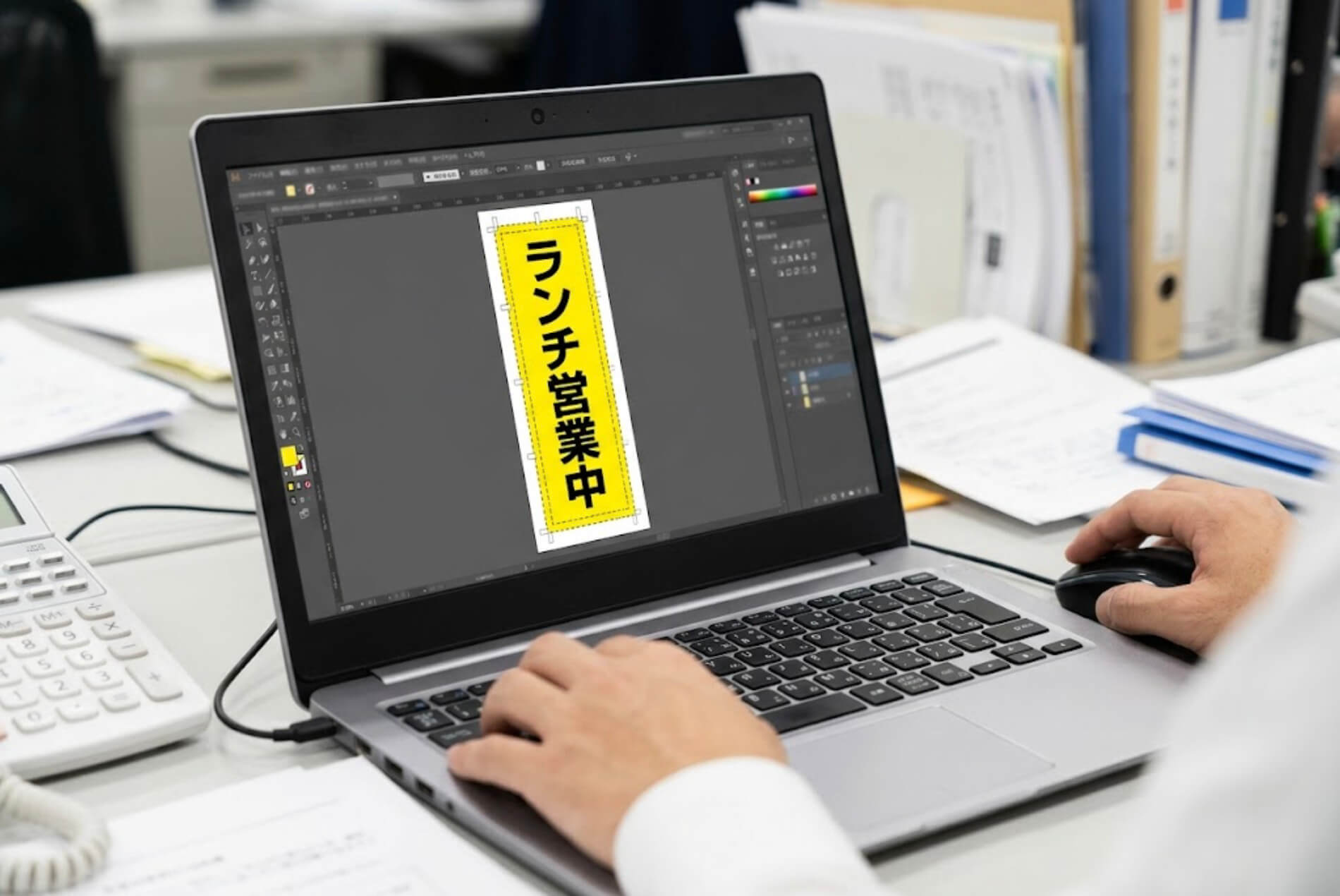パソコンの画面に縦長ののぼりのテンプレートを表示し、文字の配置を調整している手元の様子