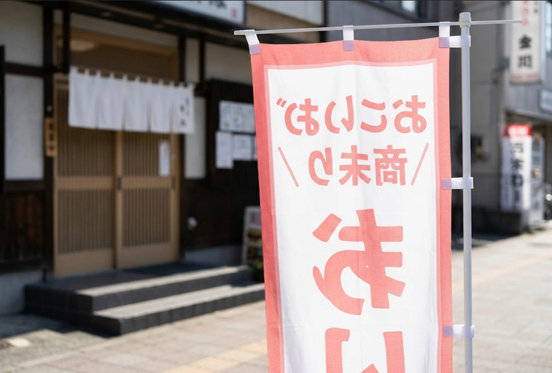 歩道側から見たのぼり旗の裏面で、文字が左右反転して透けて見えている様子
