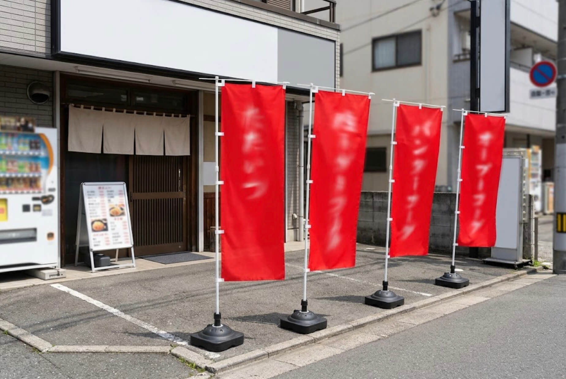 飲食店の店先の敷地内に、赤いのぼり旗が3本並んで立っている様子