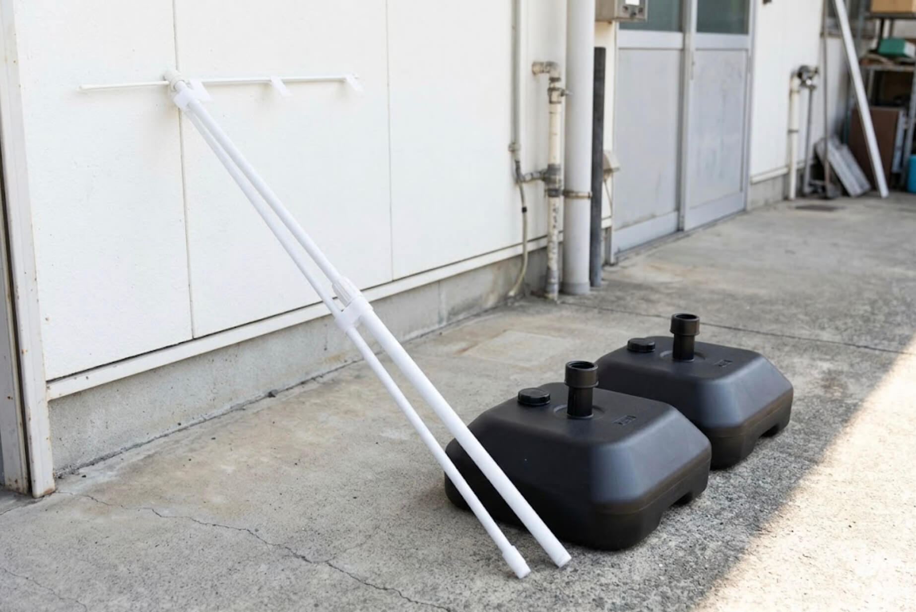 白いのぼりポール2本と、黒い注水台が並べて置かれている様子