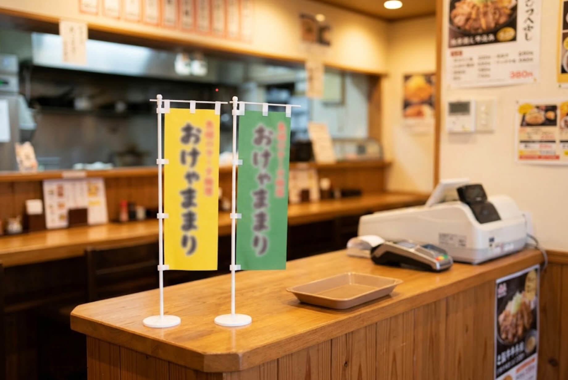 飲食店のレジ横のカウンターに、小さな卓上ミニのぼりが2本立っている様子