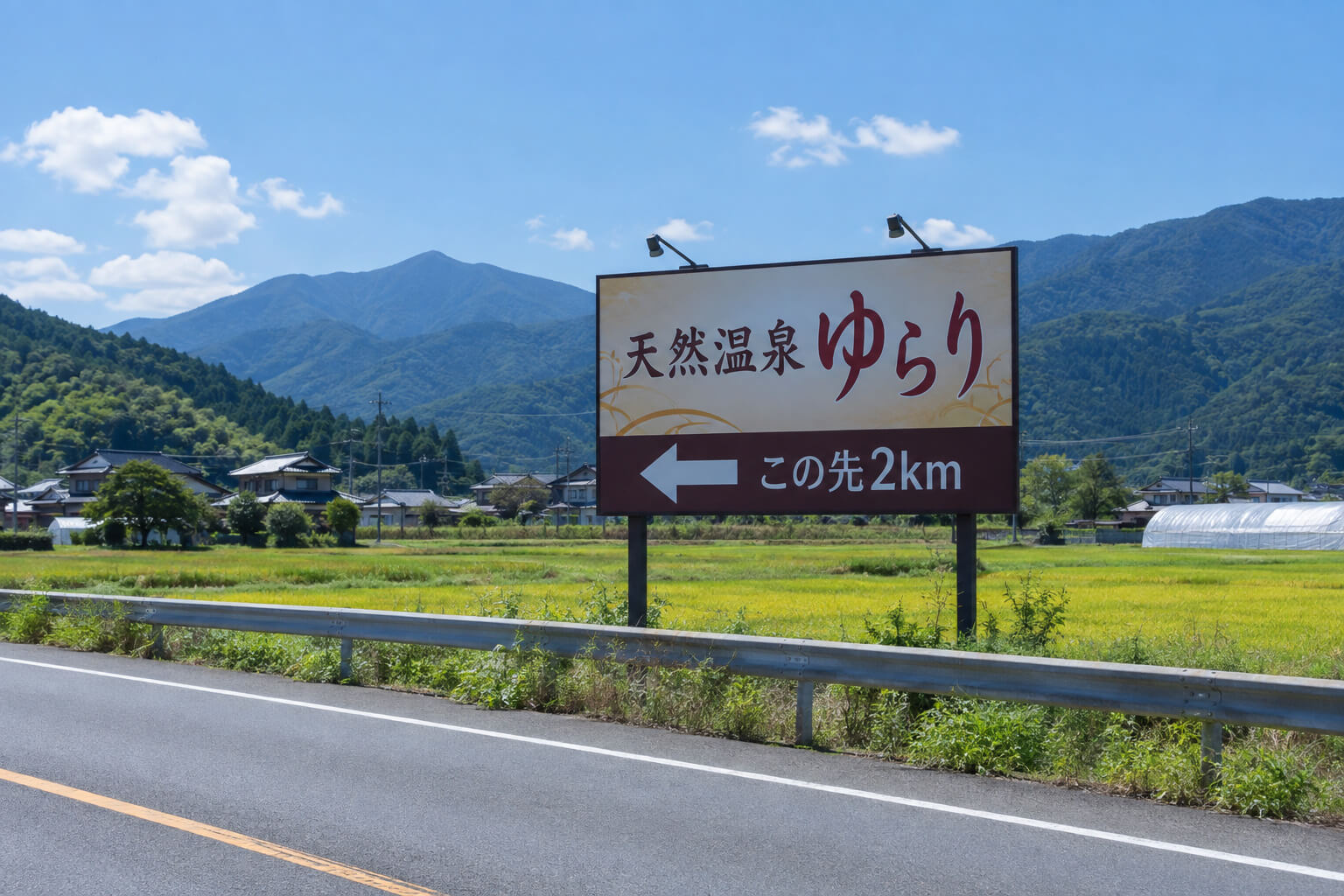 郊外の国道沿いの田園地帯に立つ、矢印と「この先2km」の文字が入った野立て看板