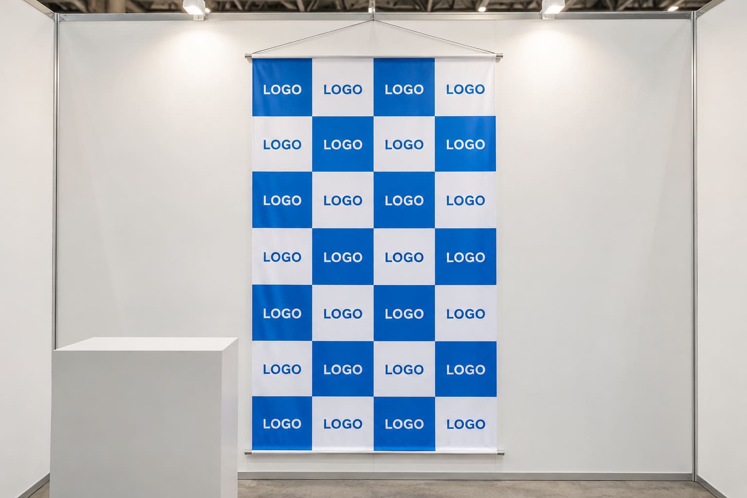 白と青の格子にロゴを並べた大判のタペストリーが、展示会ブースの正面の壁に掛かっている様子