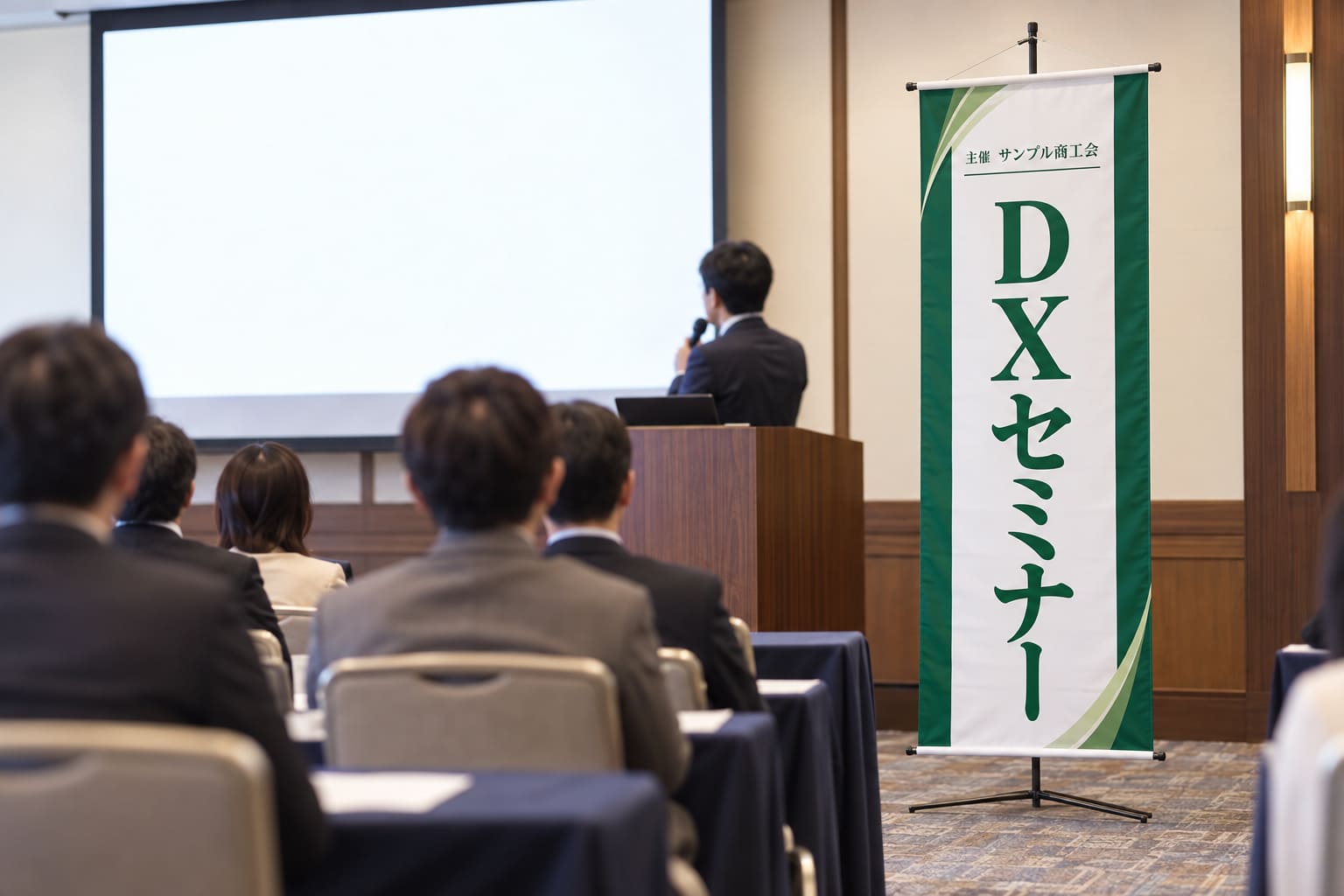 セミナー会場の演台の横に、テーマ名を大きく入れた縦長のタペストリーがスタンドで立っている様子
