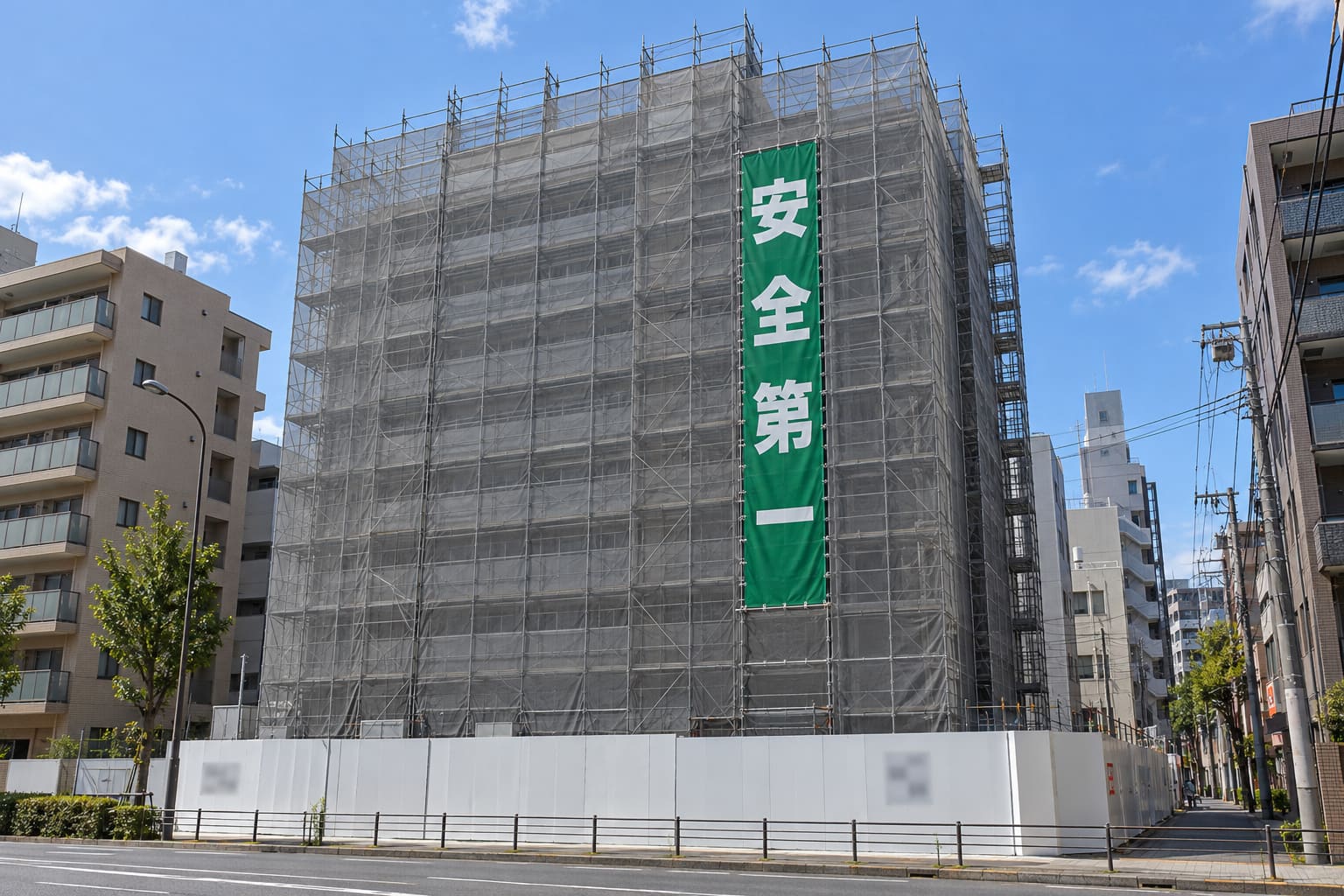建設中のビルの足場に、「安全第一」と書かれた縦長の幕が取り付けられている様子