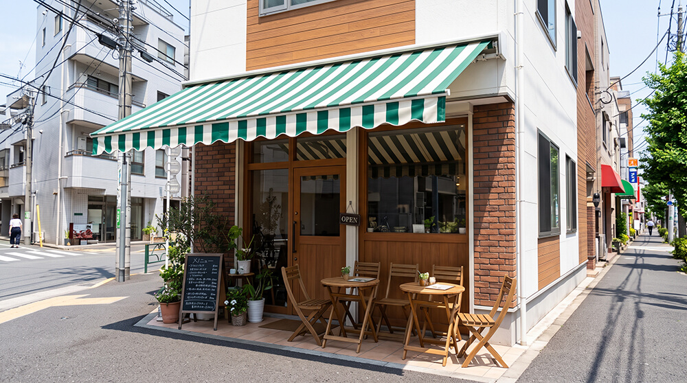 カフェの前に、ストライプのオーニングが張り出していて、その下にテラス席がある様子